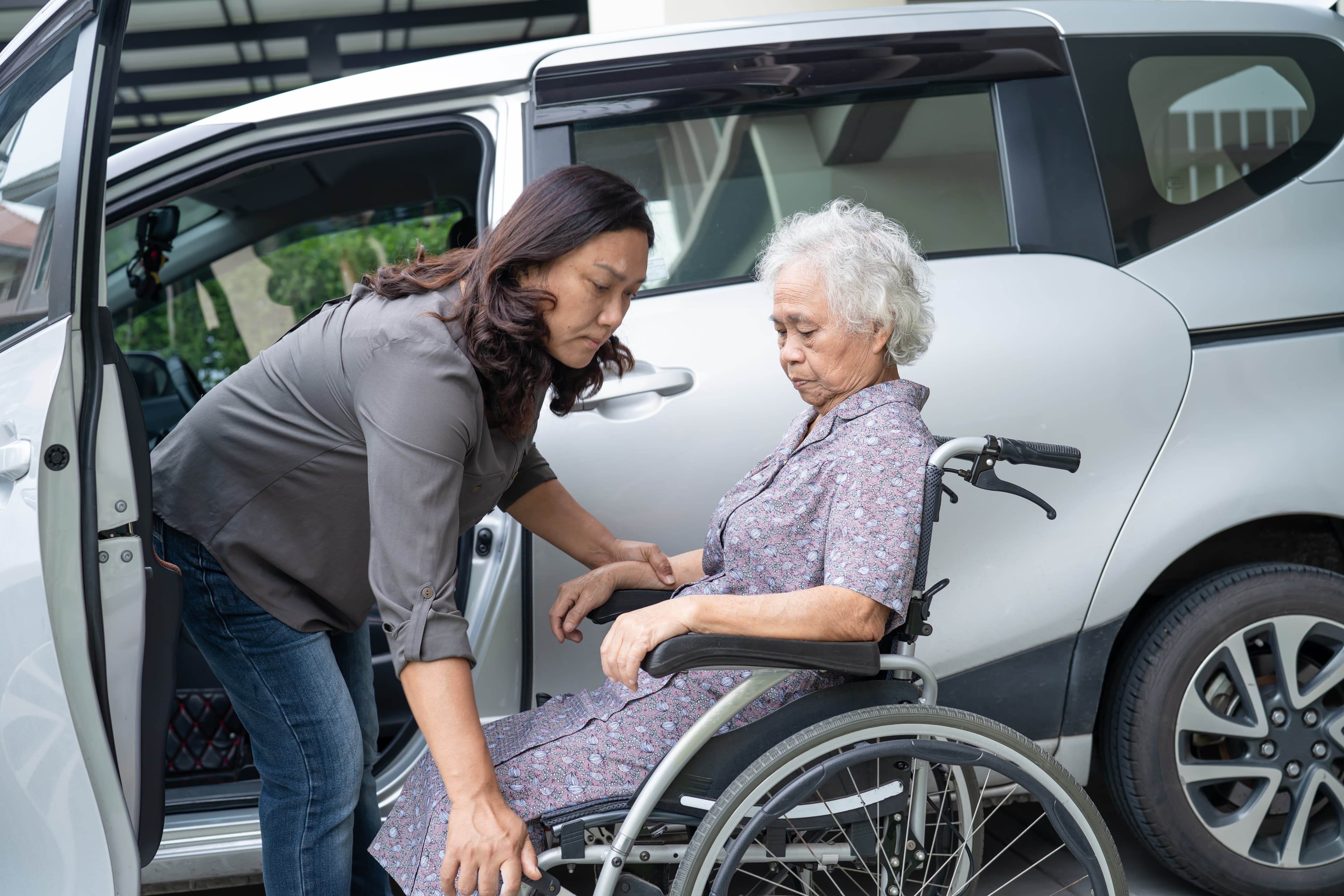 Caregiver helping an elderly client with safe transportation